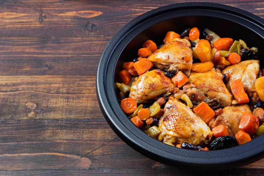 Tagine with cooked chicken and vegetables. Traditional moroccan cuisine. Wooden background Copy space.